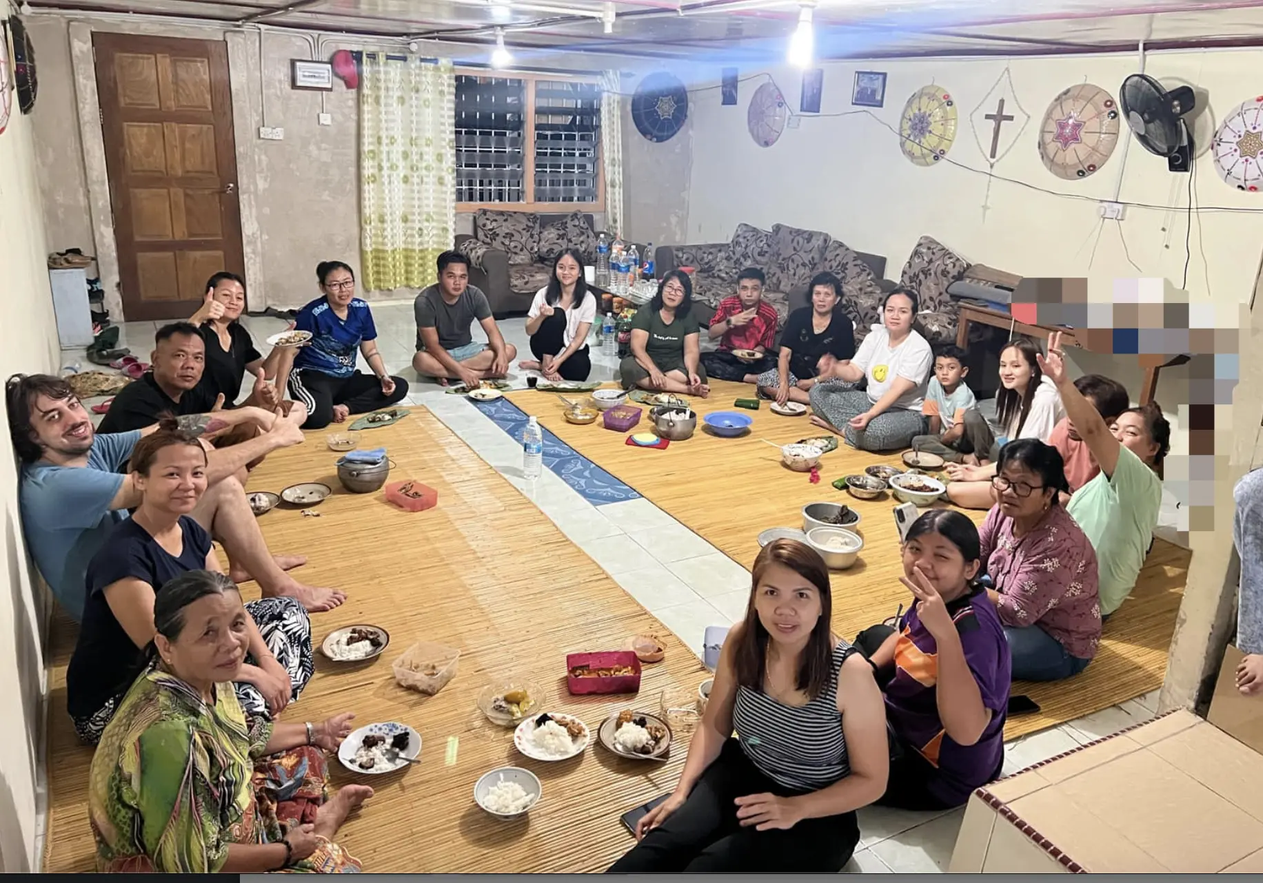 group of people seated on the floor in a large circle enjoying a meal